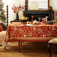 a dining room table covered with a red and gold christmas tablecloth next to a fireplace