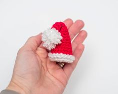 a hand holding a tiny crocheted santa hat