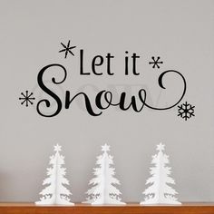 a wall decal with the words let it snow in black and white, surrounded by trees