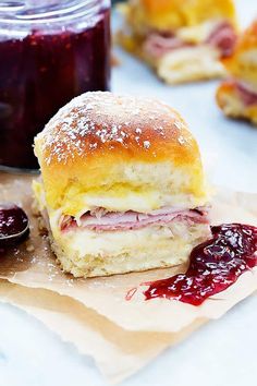 ham and cheese sandwich with jelly jam on napkins next to jar of jelly sauce