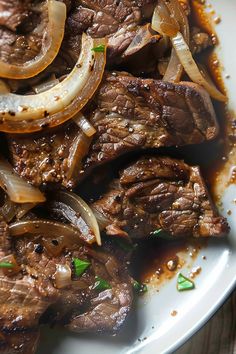 steak and onions on a white plate with brown gravy over it, ready to be eaten