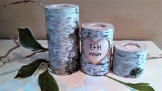 three birch tree trunks with initials on them and two candles in the shape of hearts