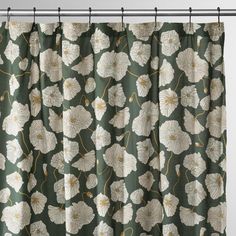 a green curtain with white flowers and gold lines on the bottom, hanging from a metal rod