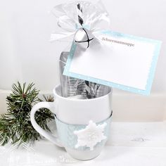 a cup filled with candy and wrapped in cellophane next to a christmas ornament