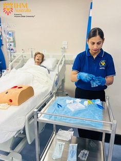 a woman in blue shirt and gloves standing next to a hospital bed with an iv bag on it