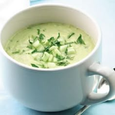 a white cup filled with soup and garnished with green leaves on the side