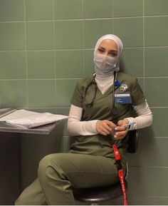 a woman in scrubs sitting on a chair with a medical mask over her face