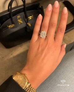 a woman's hand with a diamond ring on top of her wrist next to some purses