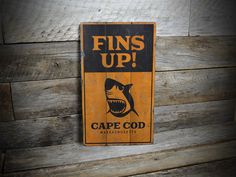 a sign that says fins up with a shark in the center and words cape god on it