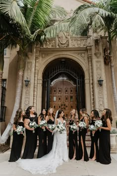 a bride and her bridal party in front of an ornate building with palm trees