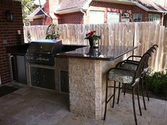 an outdoor kitchen with grill and bar stools