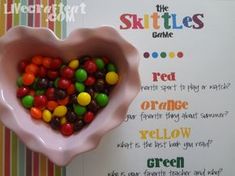 a pink bowl filled with candy sitting on top of a table next to a sign