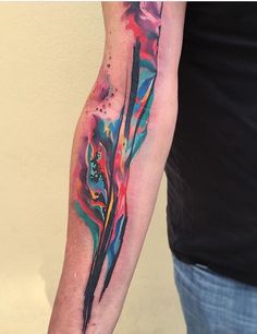 a man's arm with colorful ink on it and an abstract tattoo design in the middle