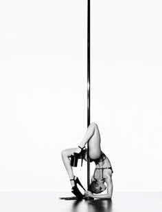 a woman leaning up against a pole with her legs spread out and one leg bent over the pole