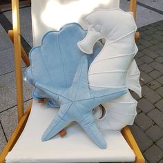 a beach chair with sea shells and starfish on it's back, sitting on the sidewalk