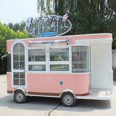 a pink and white food truck parked in front of a tree