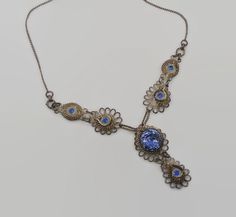 "This is a beautiful 1930 vintage necklace!  This is done in the Cennetille method of wire work.  It is ornate with twists and curls.  The large blue piece is a Czech glass piece with a flower.  Very pretty!  The other blue pieces are not glass. I have not tested the silver but I am assuming it is a low grade silver.  Very pretty unique piece.  It maintains it's original patina and I have not cleaned it. Neck length:  19\" long, pendant section 2\" long Condition:  good vintage condition, vintage patina Weight: 15.3 grams Please view enlarged photos for details and condition.  Much more beautiful in real life! I am not an expert on vintage jewelry, but I do buy and sell what I love! Since these items are vintage, they may have a wonderful aged patina and are not meant or expected to look b Vintage Metal Wire Wrapped Necklaces, Antique Blue Necklace With Intricate Design, Vintage Metal Wire Wrapped Necklace, Handmade Victorian Blue Necklaces, Vintage Wire Wrapped Metal Necklace, Handmade Victorian Blue Necklace, Blue Victorian Metal Jewelry, Ornate Blue Necklace With Intricate Design, Vintage Blue Filigree Jewelry