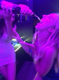 two young women drinking from bottles in a nightclub