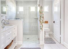 a white bathroom with a walk in shower next to a toilet