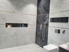 a bathroom with a toilet, sink and shower head mounted to the side of the wall