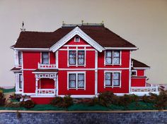 a red house with white trim on the roof and windows, in front of a brick wall