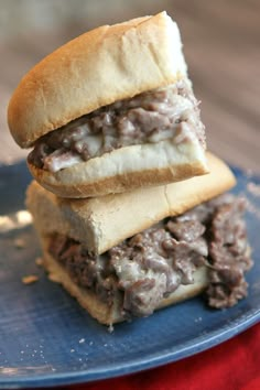 two sandwiches stacked on top of each other on a blue plate with a red cloth