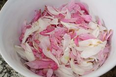 a white bowl filled with pink flowers on top of a counter