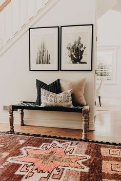 two paintings on the wall above a bench in a room with wooden floors and stairs