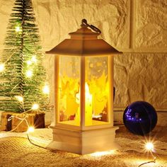 a lit lantern sitting on top of a table next to a christmas tree