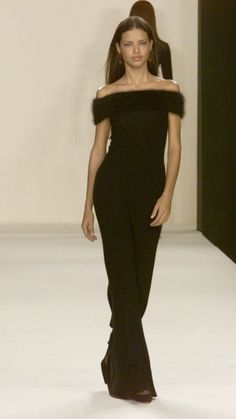 a woman walking down a runway in a black dress