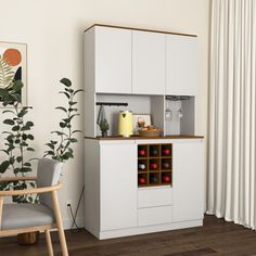 a kitchen with white cupboards and wooden flooring next to a potted plant