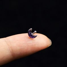 a person's finger with a small purple ring on it