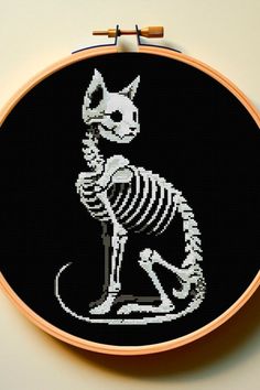 a cross stitch skeleton cat sitting on the ground