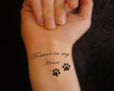 a woman's arm with a tattoo that says forever in my heart and paw prints