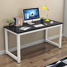 a black and white desk with a computer monitor on it's side, next to a rug