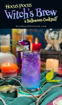 witches brew halloween cocktail with purple and blue liquid in a glass, surrounded by candles