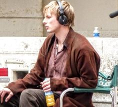 a man with headphones sitting on a bench next to a microphone and water bottle