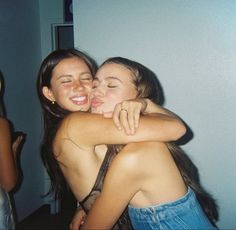 two young women hugging each other in front of a mirror and one is wearing a blue jean skirt