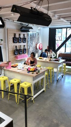 a woman sitting at a table with yellow stools