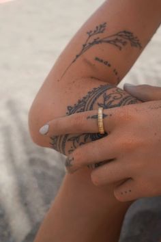 a person with tattoos on their arms holding onto a cell phone and wearing a gold ring