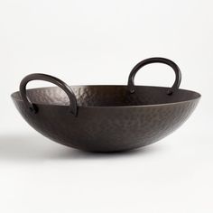 a large metal bowl with two handles on the side and an oval handle in the middle