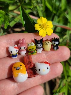 a hand holding a bunch of small toy animals in it's palm next to a yellow flower