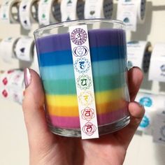 a person holding a rainbow colored candle in front of a wall with stickers on it