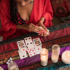 a woman sitting at a table with cards and candles