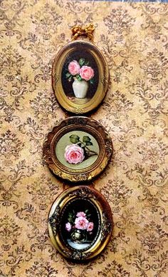 three framed pictures with pink roses in them sitting on a floral wallpapered floor