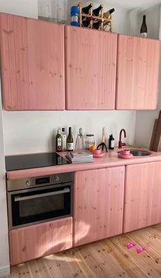 a kitchen with pink cabinets and wooden floors