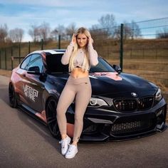 a woman leaning on the hood of a car