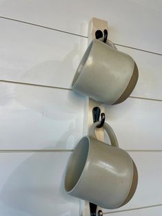 two cups are hanging on the wall with hooks