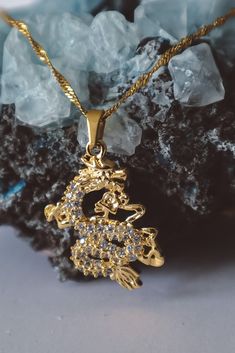 Introducing our Asian Dragon Pendant Necklace, a symbol of fire and strength.  This exquisite pendant features a majestic dragon intricately designed with zircon stones, symbolizing its fiery power and resilience.  Crafted with high-quality stainless steel, this pendant is not only stunning but also durable. The 18-inch twisted chain adds elegance to this piece, ensuring it complements any outfit.  Embrace the benefits of stainless steel, such as its resistance to tarnishing and hypoallergenic properties, making this pendant a timeless addition to your collection.  Wear this symbol of the dragon with pride and style. General Information about Solistial: Our products are known to attract compliments, making you shine with confidence and style. 🤍 We take pride in our eco-conscious process a Layer Necklace Gold, Majestic Dragon, Necklace Gold Jewelry, Twisted Chain, Gold Schmuck, Asian Dragon, Layer Necklace, Dragon Jewelry, Dragon Pendant