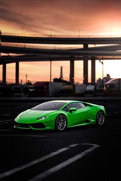 a green sports car is parked in the parking lot at sunset, with an overcast sky behind it